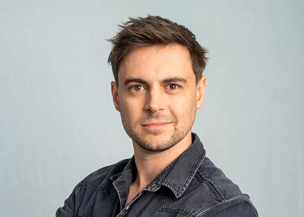 Photograph of Will Hayward wearing Gray shirt with a light coloured background